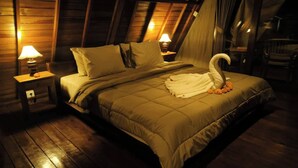 A cozy room with a bed, two bedside lamps, and a swan-shaped pillow. - Lumbung Sari Ubud 2

 (Bali)