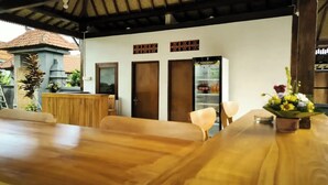 A dining area with a wooden table and chairs, a refrigerator, and a small plant. - Lumbung Sari Ubud 2

 (Bali)