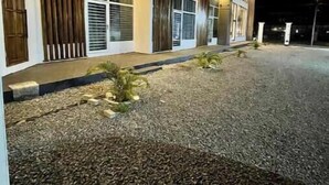 Un edificio moderno con camino de grava y un pequeño jardín.