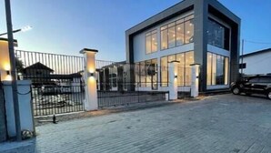 Un edificio moderno de dos pisos con amplios ventanales y un área de entrada pavimentada.
