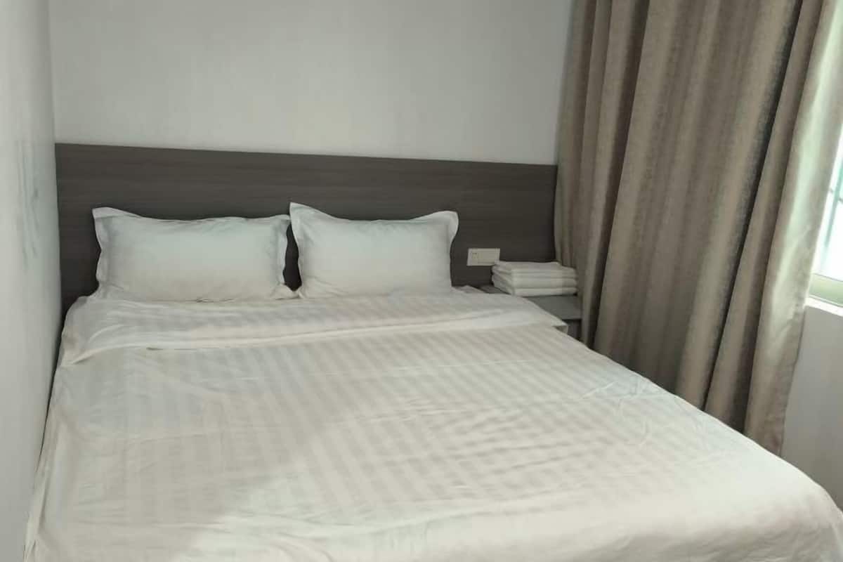 A neatly made bed with a headboard, pillows, and a folded blanket.