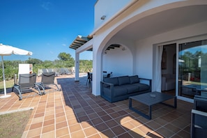 An outdoor patio area with a sofa, chairs, and a table.