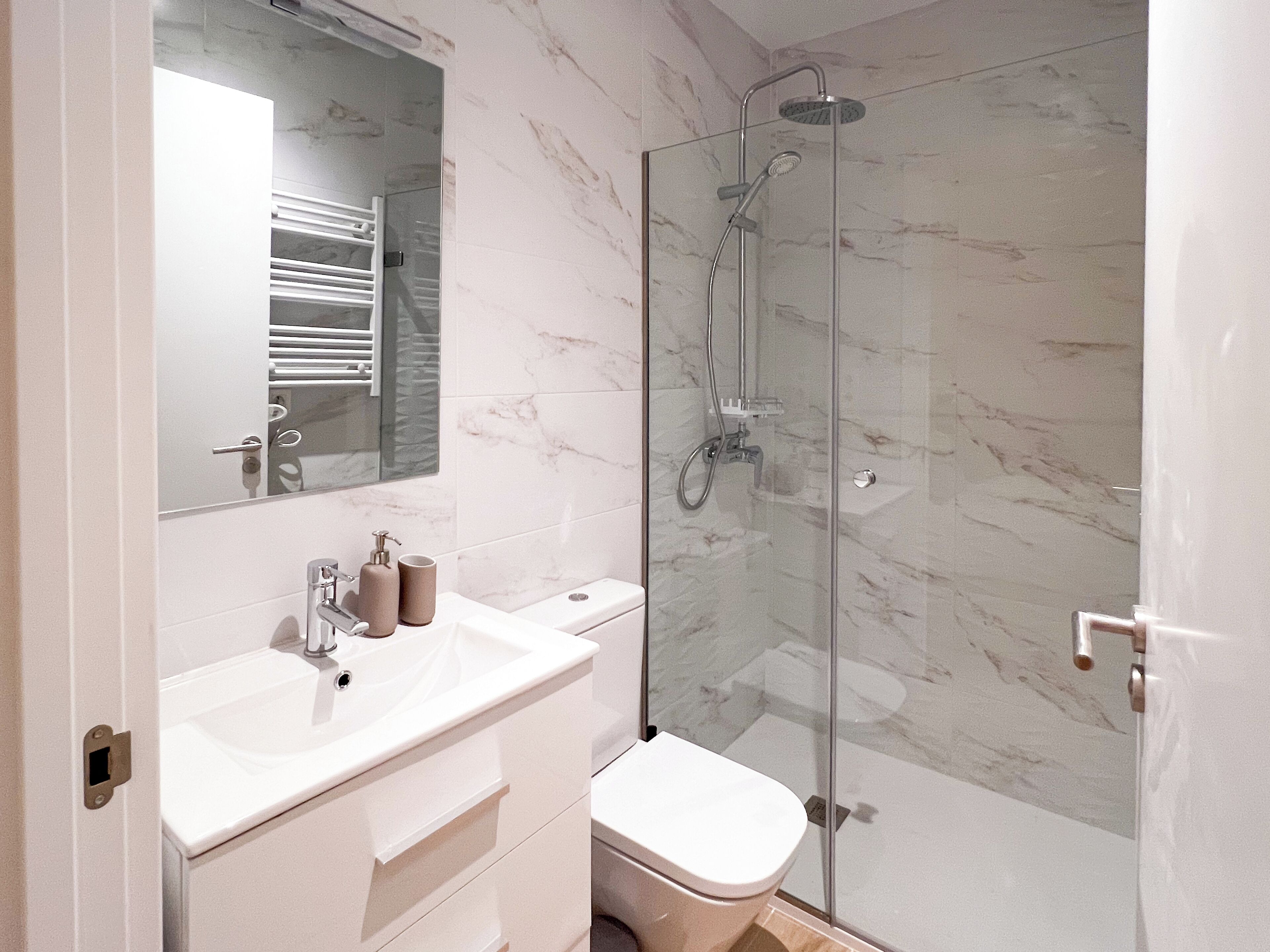 Une salle de bain moderne avec une douche à parois de verre, un lavabo blanc et des toilettes.