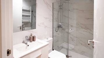 Une salle de bain moderne avec une douche à parois de verre, un lavabo blanc et des toilettes.