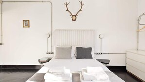 Un dormitorio moderno con una cama grande, una cabeza de ciervo montada en la pared y un aparador minimalista.