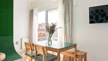 Een moderne eethoek met een glazen tafel, houten stoelen en een vaas gedroogde planten.