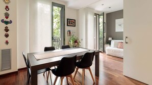 Ein moderner Essbereich mit einem langen Tisch, schwarzen Stühlen und Blick auf einen Balkon.