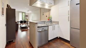 Eine moderne Küche mit Geschirrspüler, Kühlschrank und Essbereich mit Tisch und Stühlen.