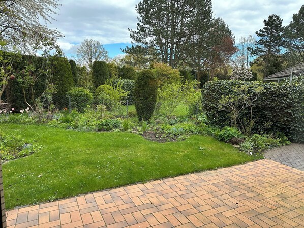 Un jardin bien entretenu, avec une grande variété de plantes et une terrasse dallée.
