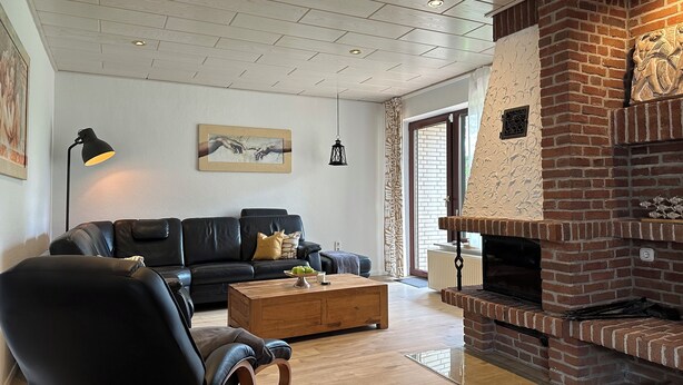 Un salón con un sofá de cuero negro, una mesa de centro de madera y una chimenea de ladrillo.