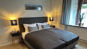 Un dormitorio moderno con una cama grande, dos lámparas de noche, una alfombra y una ventana con cortinas.