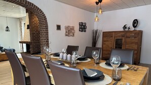 Un comedor con chimenea de ladrillo, mesa de madera y sillas modernas.