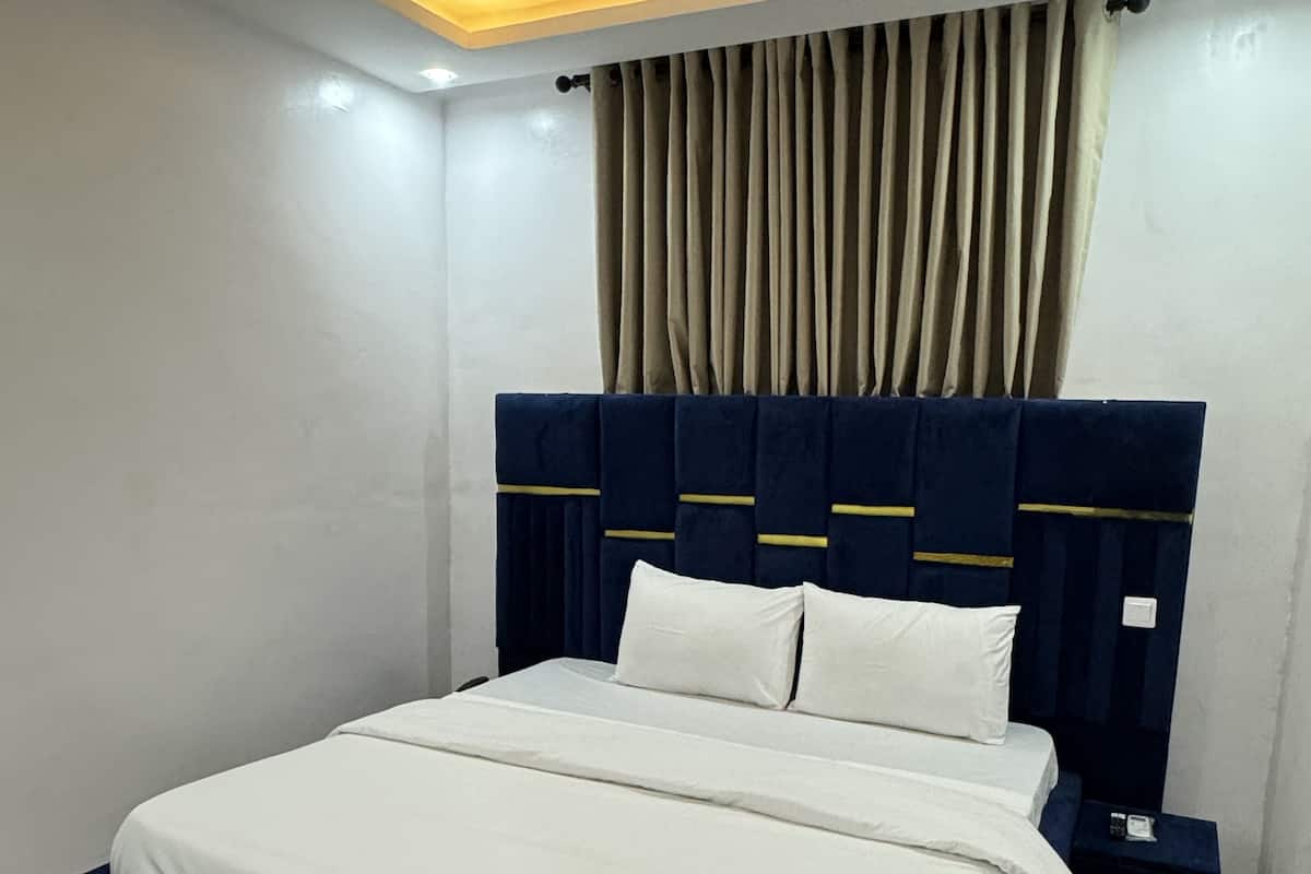 Un dormitorio moderno con una cama grande, una mesita de noche y un cabecero con iluminación integrada.