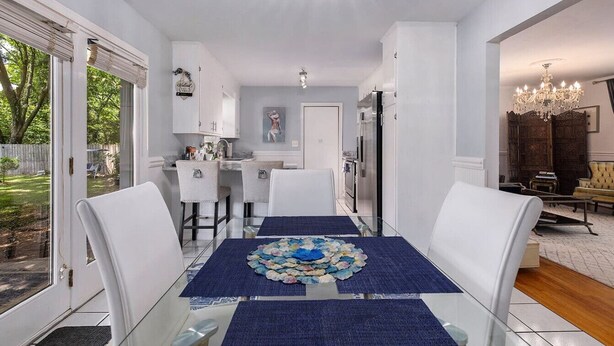A dining area with a glass table, white chairs, and a blue table runner. - Chic Southern Retreat (Charleston)