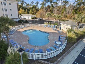 A swimming pool with lounge chairs and a fenced area, surrounded by trees and a building. - Waterview Lux Golf 3 Bdrm- Pools- Broadway @ Beach (Myrtle Beach)