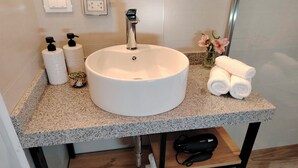 A bathroom with a round white sink, a hairdryer on a shelf, and towels on the counter. - Casa Cruz Verde by Peru Garden Hotels (Cusco)