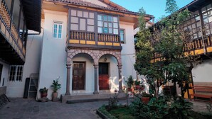 A traditional building with a courtyard, featuring a central archway, wooden doors, and potted plants. - Casa Cruz Verde by Peru Garden Hotels (Cusco)