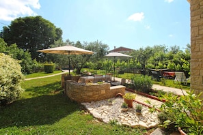 A stone fire pit with seating, surrounded by a garden with potted plants and a pathway. - Holiday apartment with parking (Muntic)