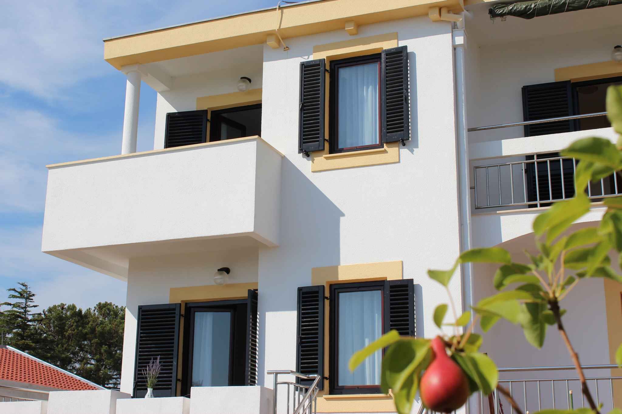 A modern two-story building with balconies and windows with shutters.