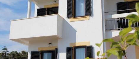 A modern two-story building with balconies and windows with shutters.