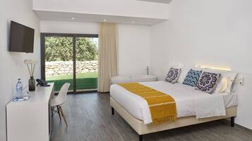 A modern bedroom with a bed, desk, chair, and a TV mounted on the wall.