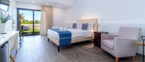 A modern hotel room with a large bed, a desk, and a chair.
