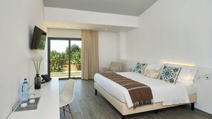 Une chambre moderne avec un grand lit, un bureau et une chaise. La fenêtre offre une vue sur la verdure.