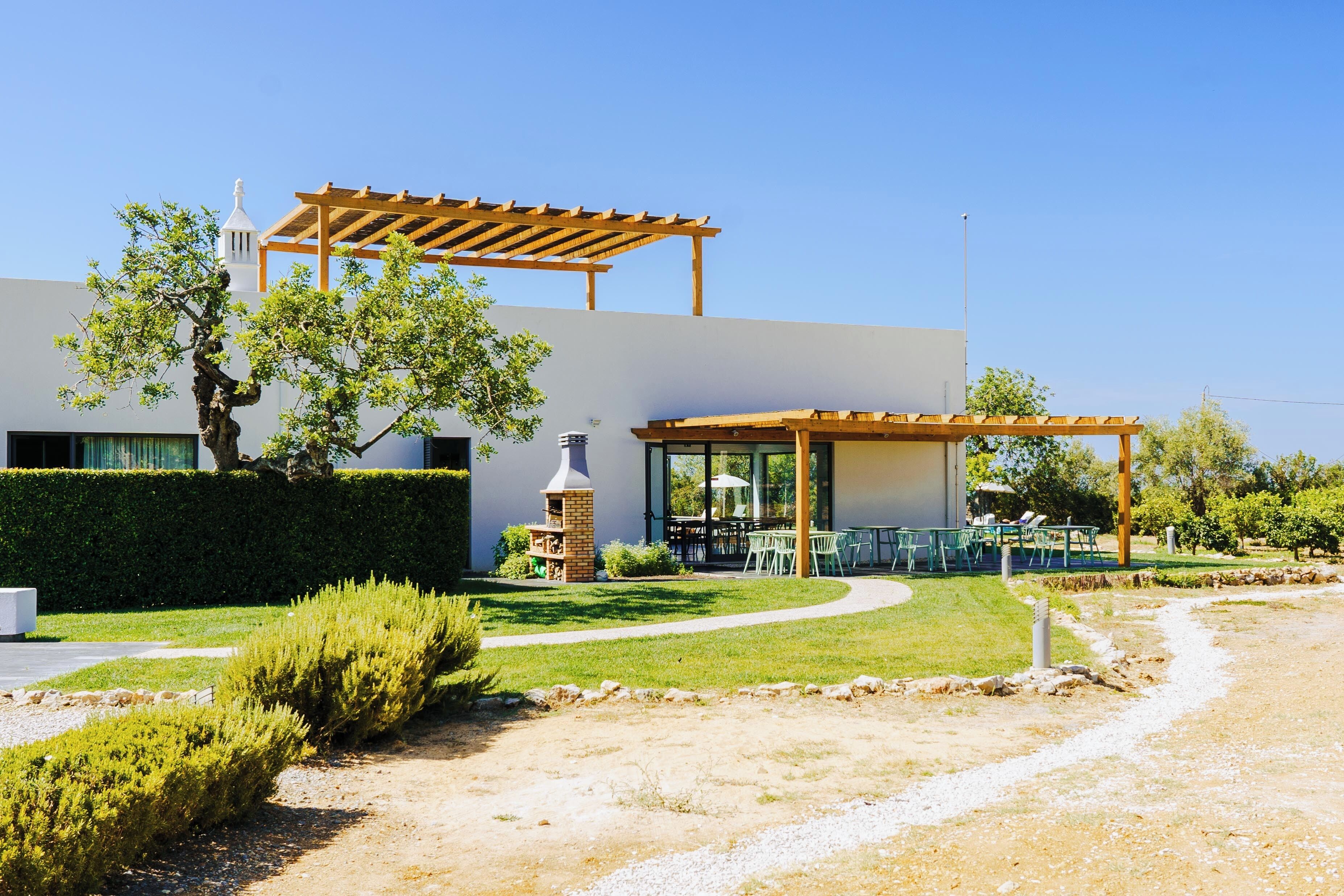Un edificio moderno con un patio cubierto, una chimenea de piedra y un césped cuidado.
