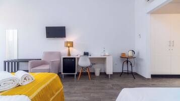 Ein Hotelzimmer mit Bett, Schreibtisch, Stuhl, Fernseher und einer kleinen Küchenzeile.