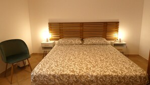 A neatly arranged bedroom with a large bed, two bedside tables with lamps, and a single chair. - Scappo in Umbria, Felicità 14a (Giove)