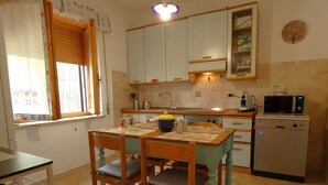 A kitchen with wooden cabinets, a microwave, and a sink. - Scappo in Umbria, Felicità 14a (Giove)