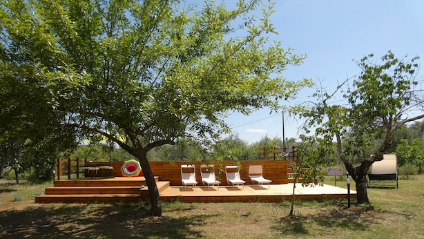Une terrasse en bois avec des sièges d’extérieur et une décoration circulaire aux couleurs vives.