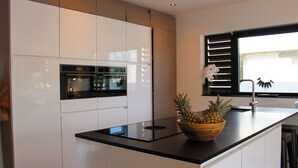 Eine moderne Küche mit weißen Schränken, einer schwarzen Arbeitsplatte und einer Holtschale mit Ananas.