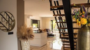 A modern interior with a kitchen island, a dining area, and a staircase. - Luxury Villa Incl Pool With Seaview Near Beaches (Grote Berg)