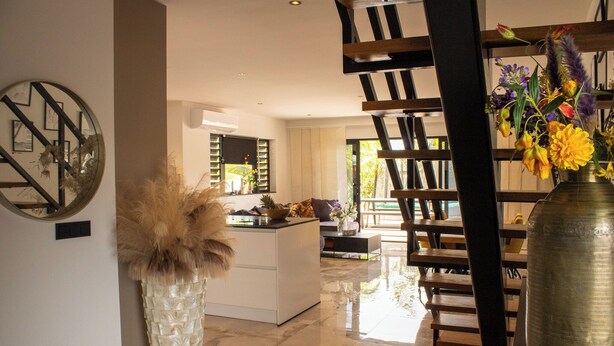 Ein modernes Interieur mit Kücheninsel, Essbereich und Treppe.