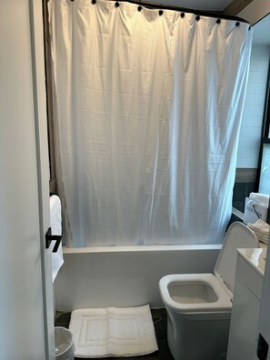 Ein Badezimmer mit Badewanne, Toilette und Duschvorhang.