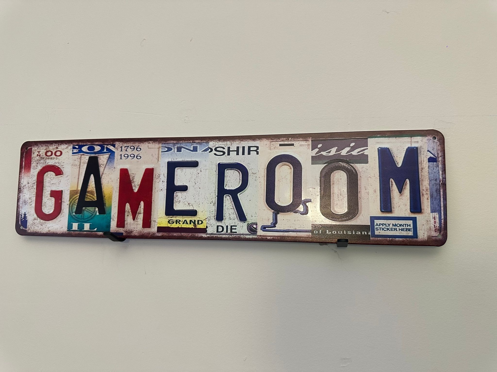 A license plate with the word 'GAMEROOM' spelled out in large letters.