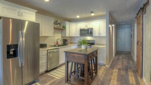 Una cocina moderna con electrodomésticos de acero inoxidable, armarios blancos y una isla de madera.