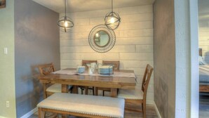 Un comedor con una mesa de madera, sillas e iluminación colgante.
