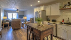 Una cocina moderna con armarios blancos, una isla de madera y un comedor con sofá y sillas.