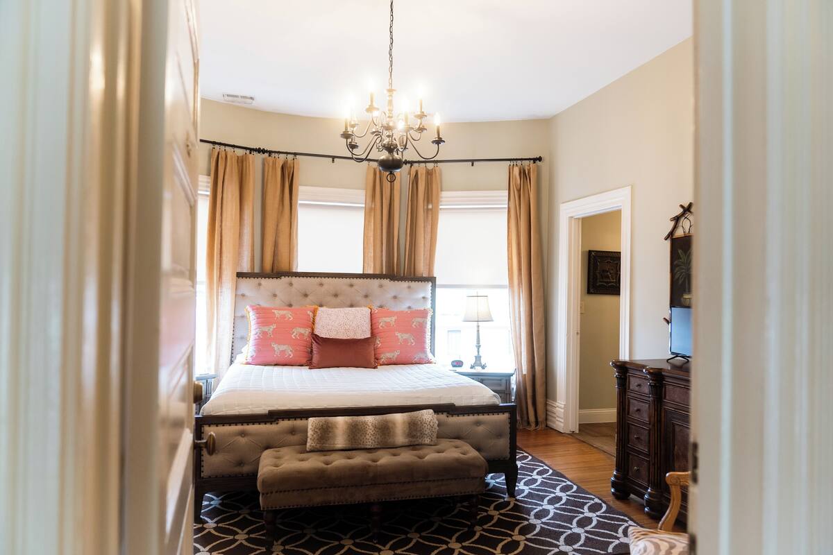 Quarto com uma cama grande, um candelabro, uma mesa de cabeceira e um armário.