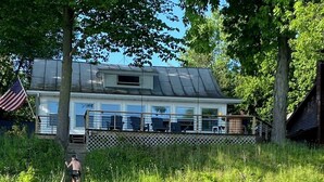 A wooden dock leading to a house with a deck and outdoor seating. - Charming Lakefront Cottage on Coldwater Lake (Coldwater)
