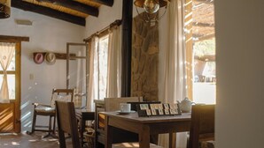 A rustic dining area with wooden furniture and a stone wall. - Loma Puskana - Hostería (Cachi)