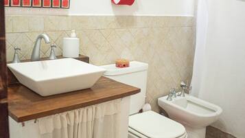 A bathroom with a sink, toilet, bidet, and a mirror with a red frame.