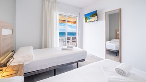 A hotel room with a bed, a bedside table with a lamp, a window with curtains, a painting, and a mirror. - Principado Arena 20 Deluxe Apartment Levante Beach (Benidorm)