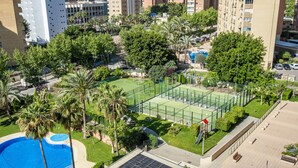 Ein Wohngebiet mit Tennisplatz, Schwimmbad und umgebender Grünfläche.