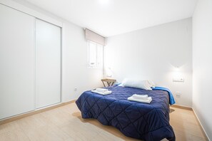 Een slaapkamer met een bed, een kledingkast, een raam en een nachtkastje.
