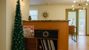 A wooden reception desk with a vintage radio, a Christmas tree, and a sign that reads "MAGIC BUS THE WHO." - Unique Dwtwn+Lake & Trails (Rogers)