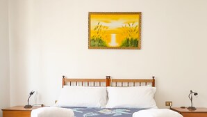 A neatly made bed with a floral bedspread, two white pillows, and two folded towels on the side.