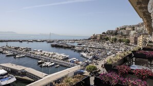 A marina with numerous boats docked, a bridge connecting to the mainland, and a cityscape with buildings in the background. - Demetra Luxury Suites (Naples)